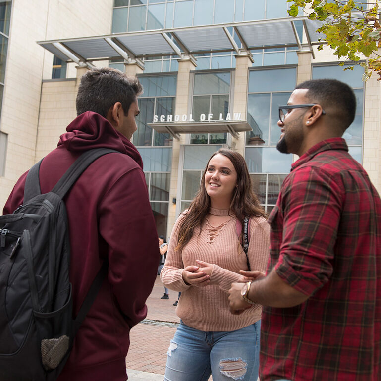 Three students standing and talking to each other outside of the law school building at Rutgers-Camden
