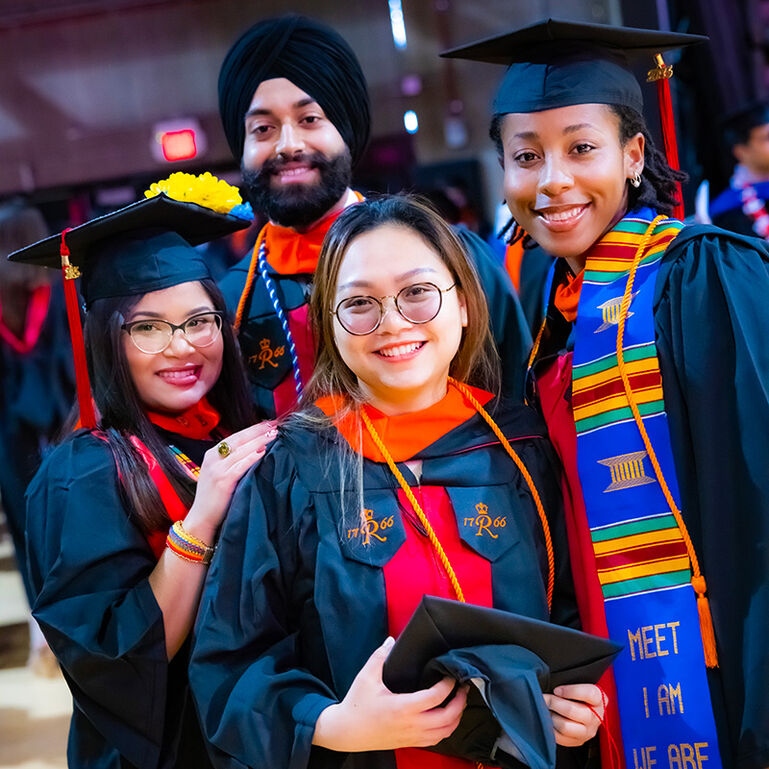Three smiling students in caps and gowns