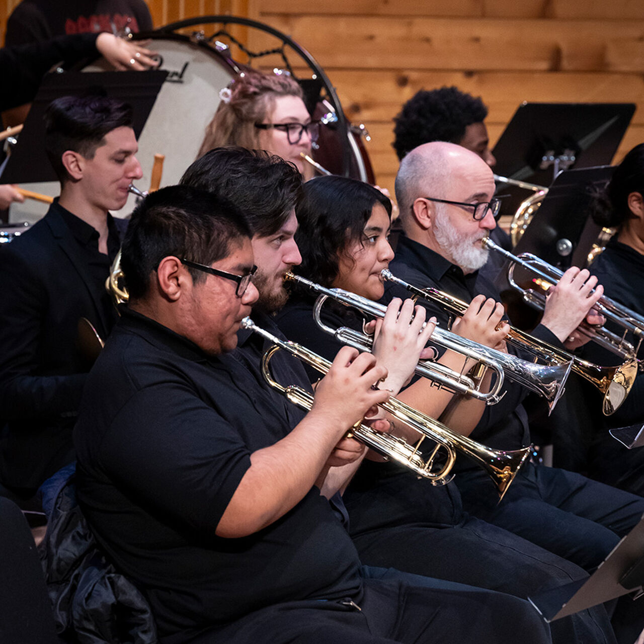 Students playing trumpet on stage in a concert band image number 0