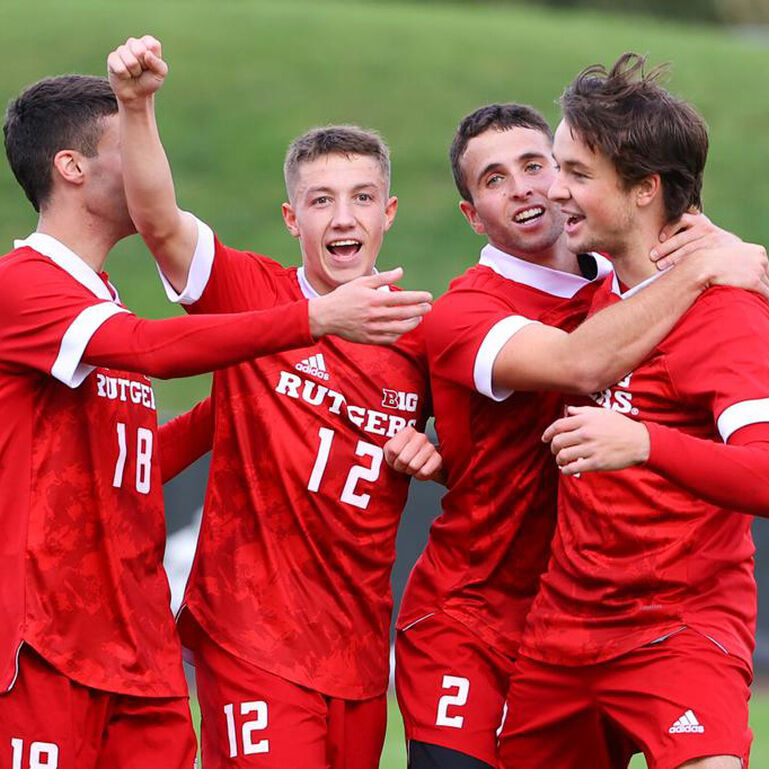 Four Rutgers Men's Soccer players cheering and hugging one another