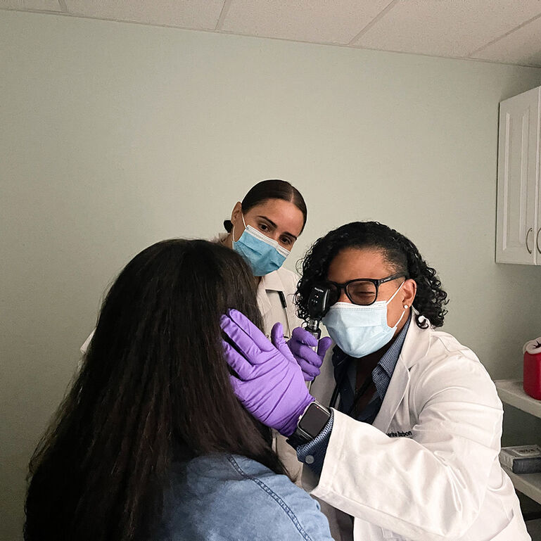Two clinicians providing an eye exam to a patient