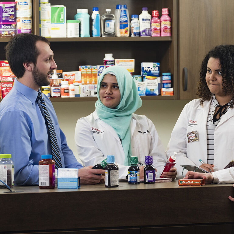 Pharmacy students working behind the pharmacy counter