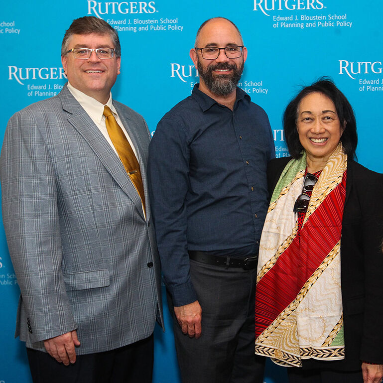 Three people standing in front of blue background