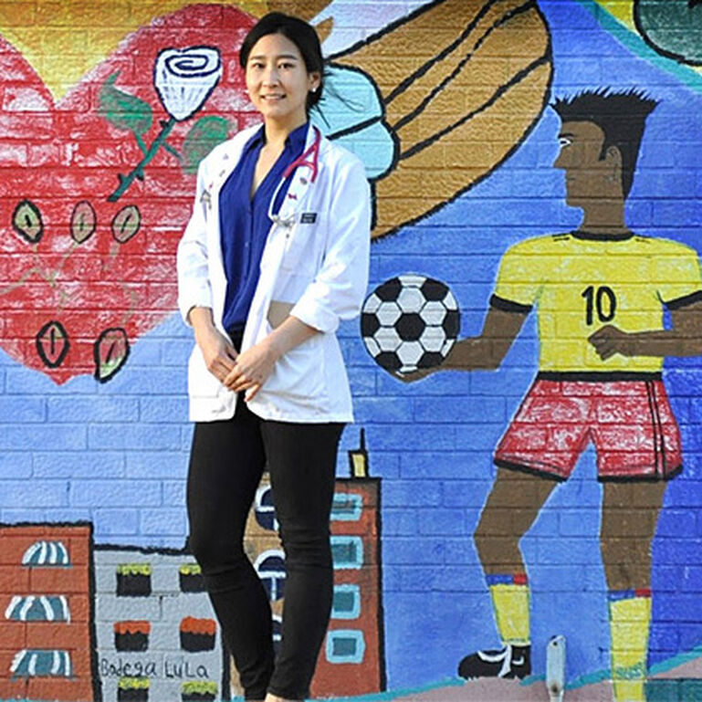 Medical student standing in front of mural