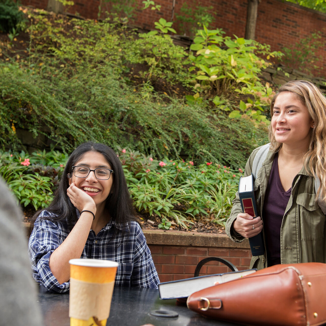 Students smiling and chatting around outdoor tables on the Rutgers Newark campus image number 0