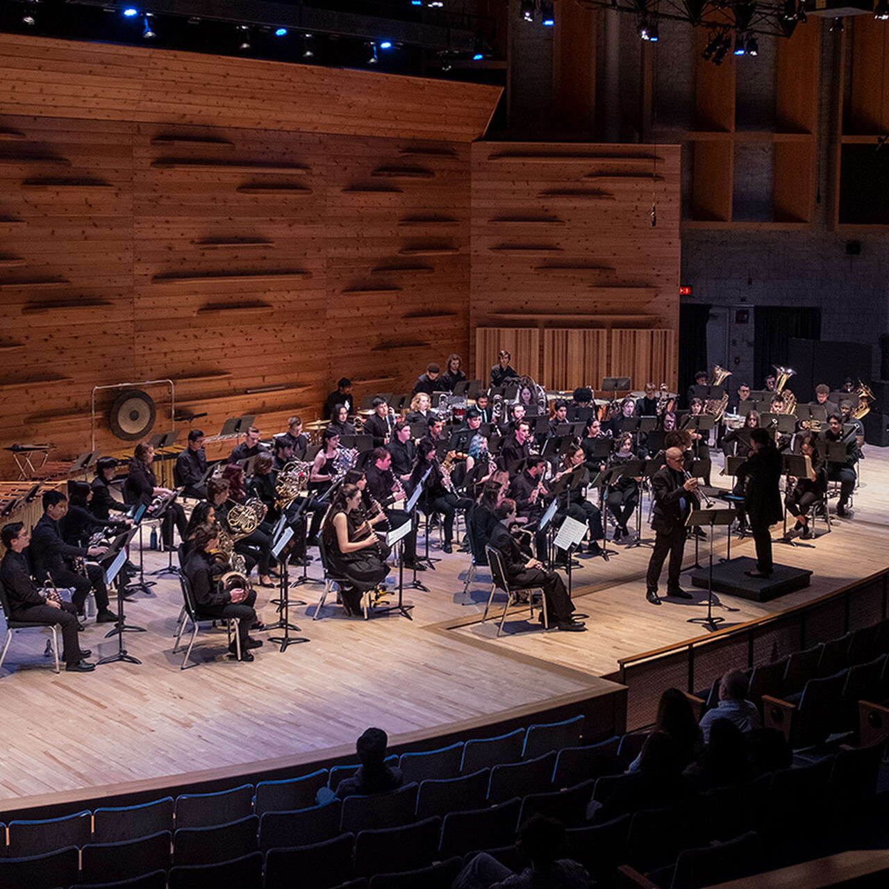 Concert band sitting on stage with their instruments image number 0