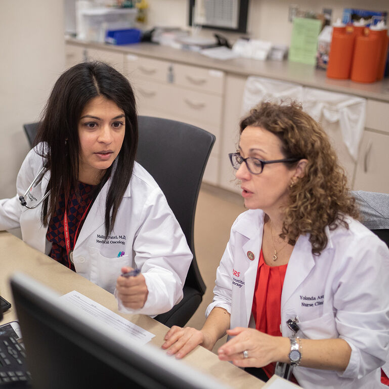 Two Cancer Institute physicians working at computer