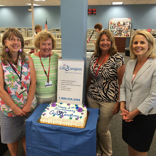 Four women standing around birthday cake image number 1