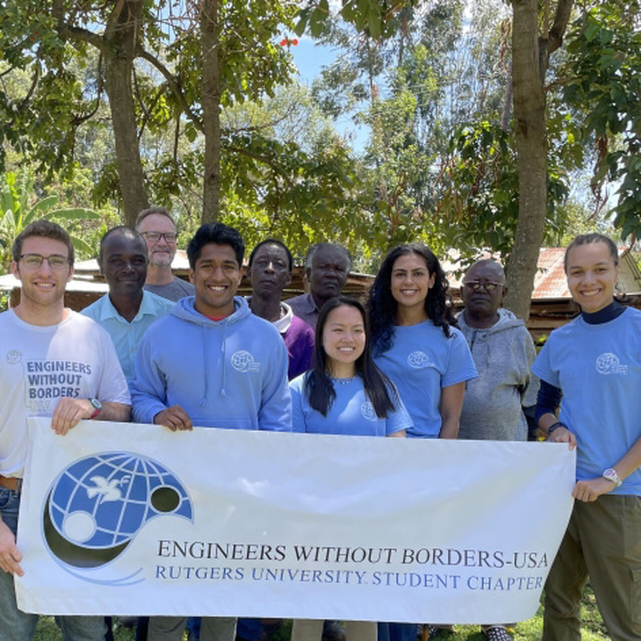 Smiling students standing behind Engineers Without Borders banner image number 0