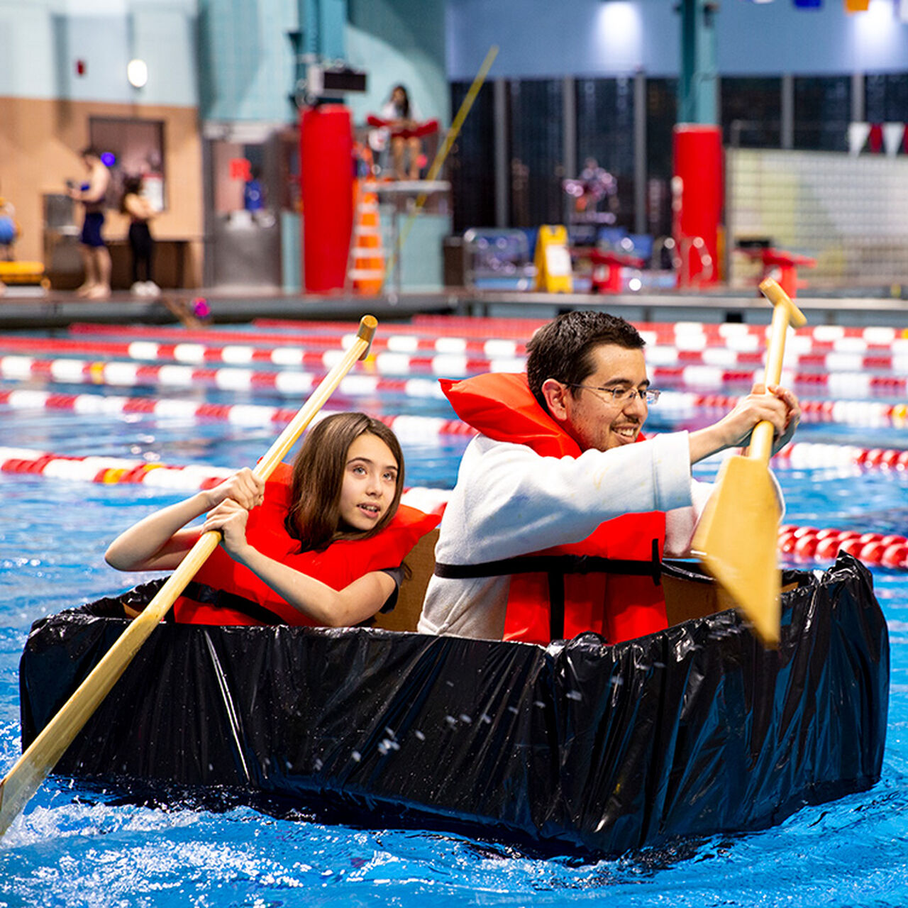 Two students paddling a makeshift canoe in a pool image number 0