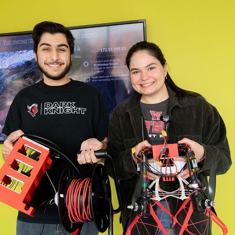2 students holding a robot and other mechanical elements in the Weeks Concept Lab