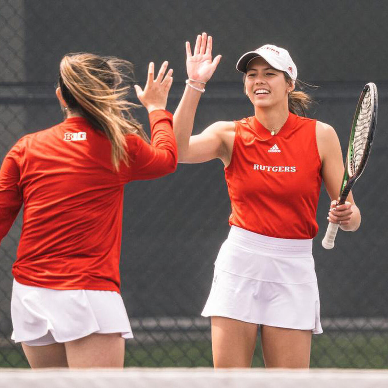 Two Rutgers Women's Tennis players high-fiving one another on the court image number 0