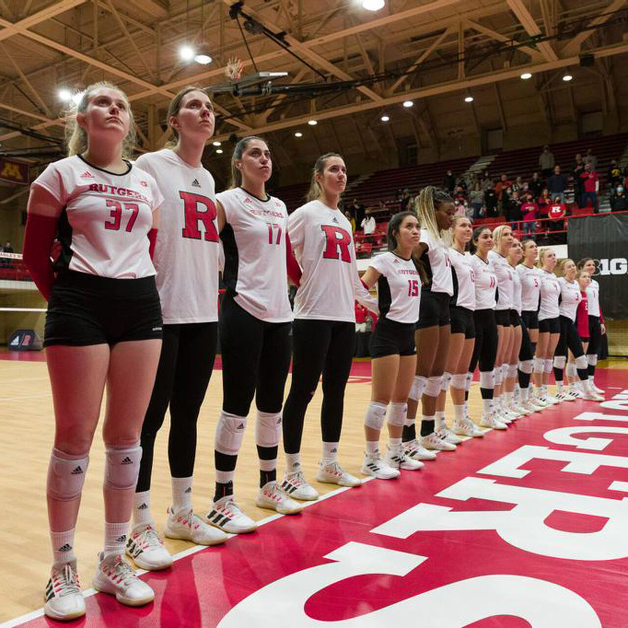 Rutgers Women's Volleyball team standing in the middle of the court in a line before a match image number 0