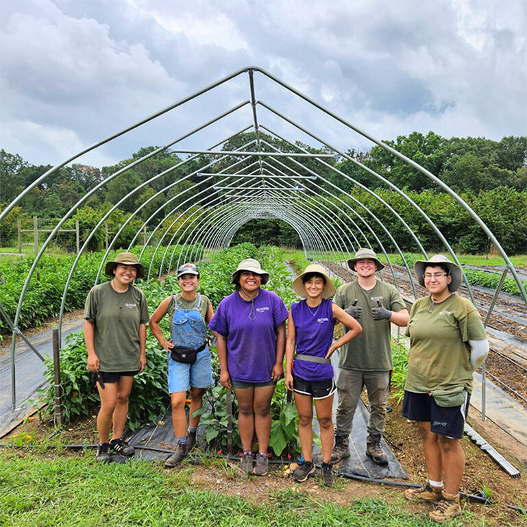 Group of students smiling at the camera at the Rutgers Gardens student farm