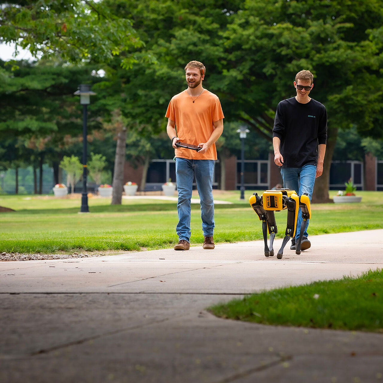 Two students walking on campus with robot dog image number 0