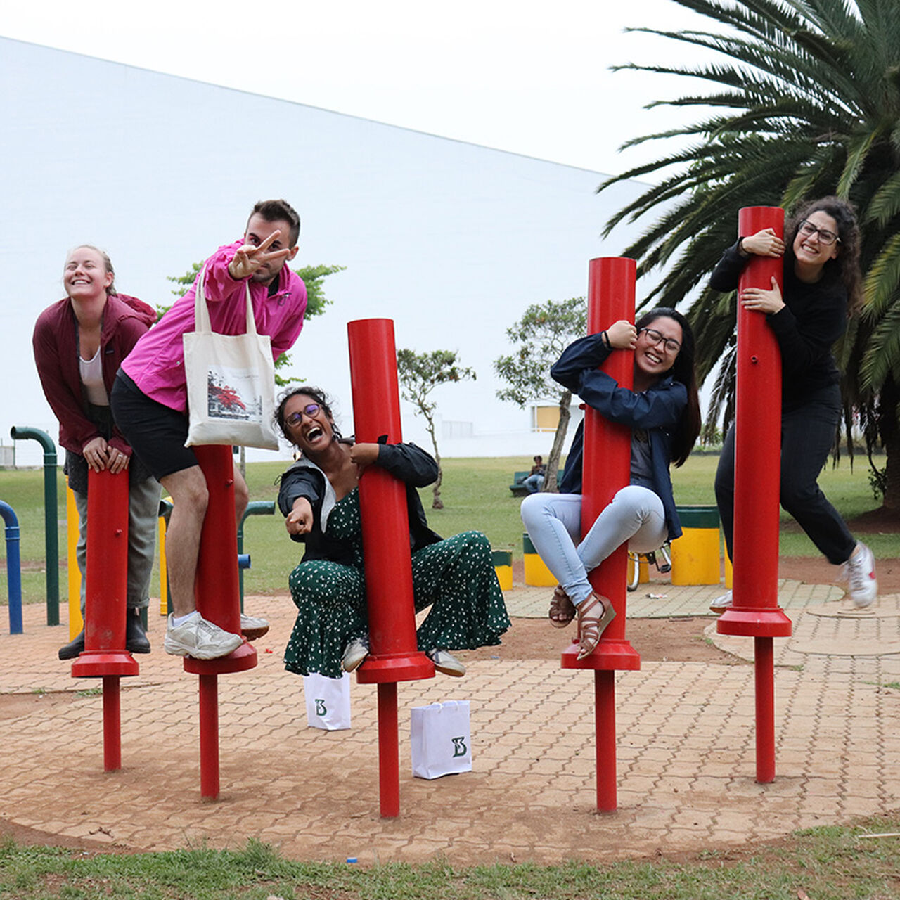 5 students standing on playground equipment smiling at the camera image number 0