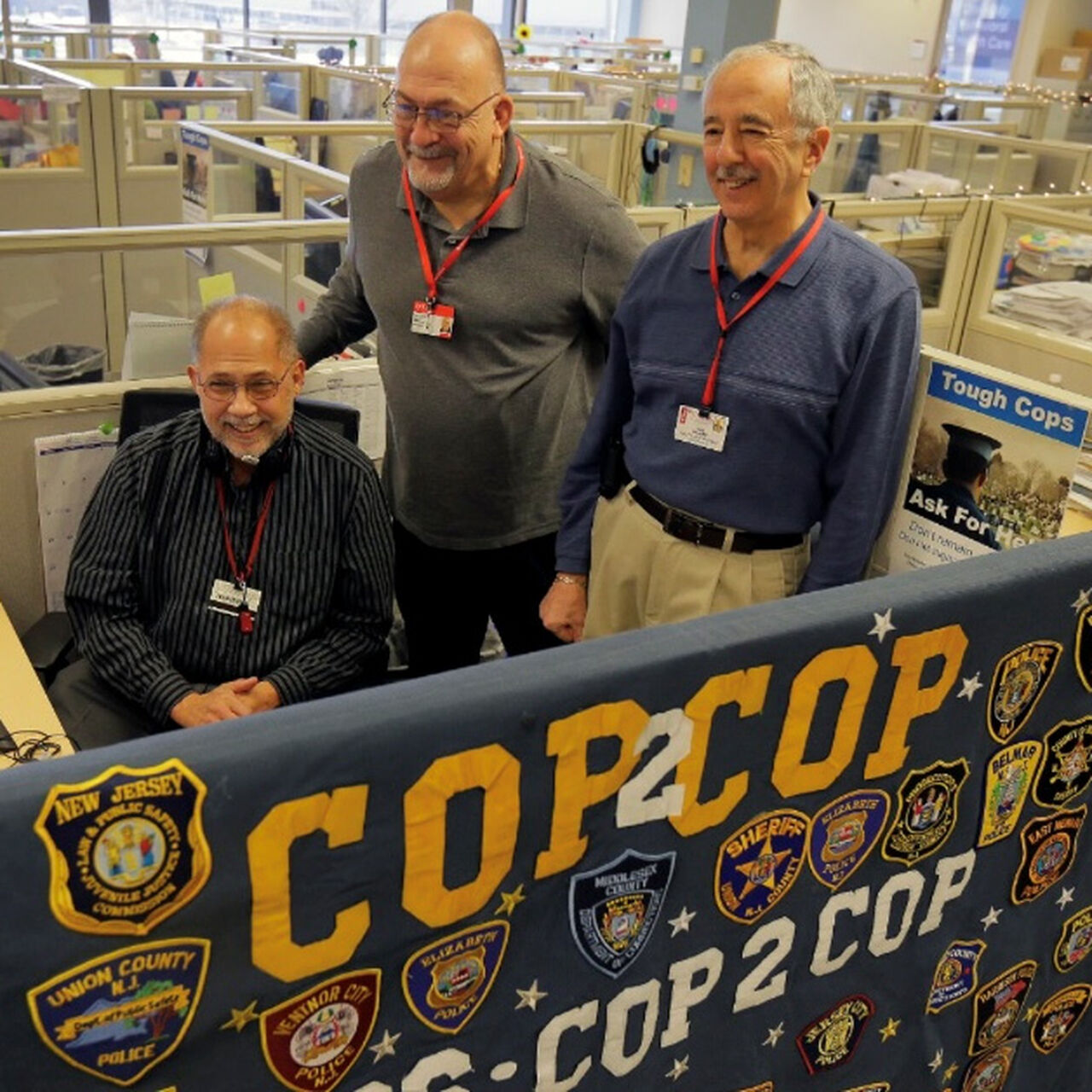 Three men behind Cop2Cop banner in call center image number 0