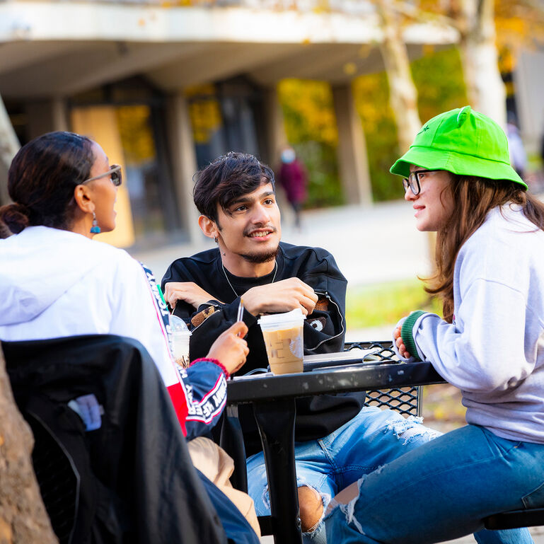 Students chatting at a table in the outdoor courtyard at Rutgers-Newark