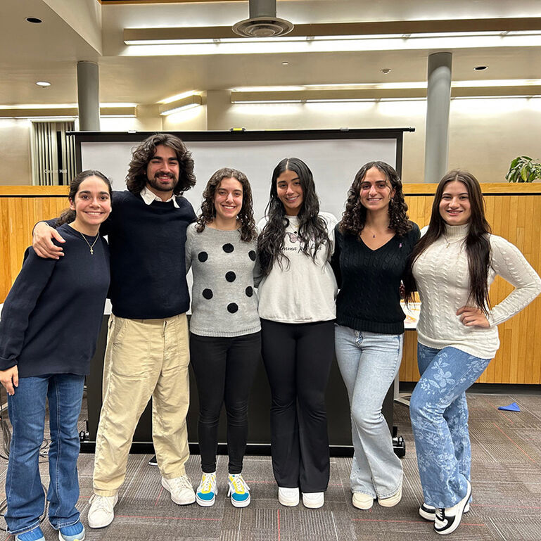 Group of students standing in a line and smiling at the camera with arms around one another