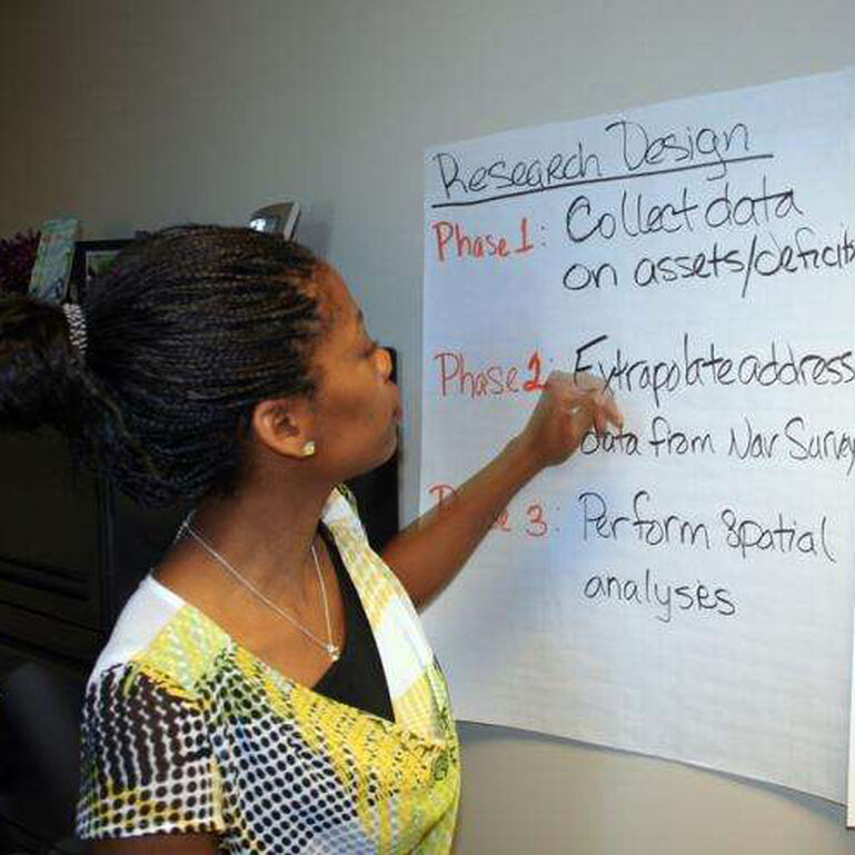 Dr. Stacia Gilliard-Matthews writing on a poster in a classroom