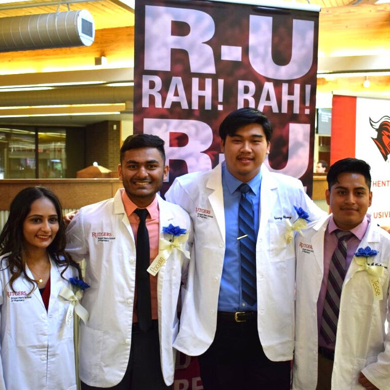 Smiling pharmacy students standing in front of banner