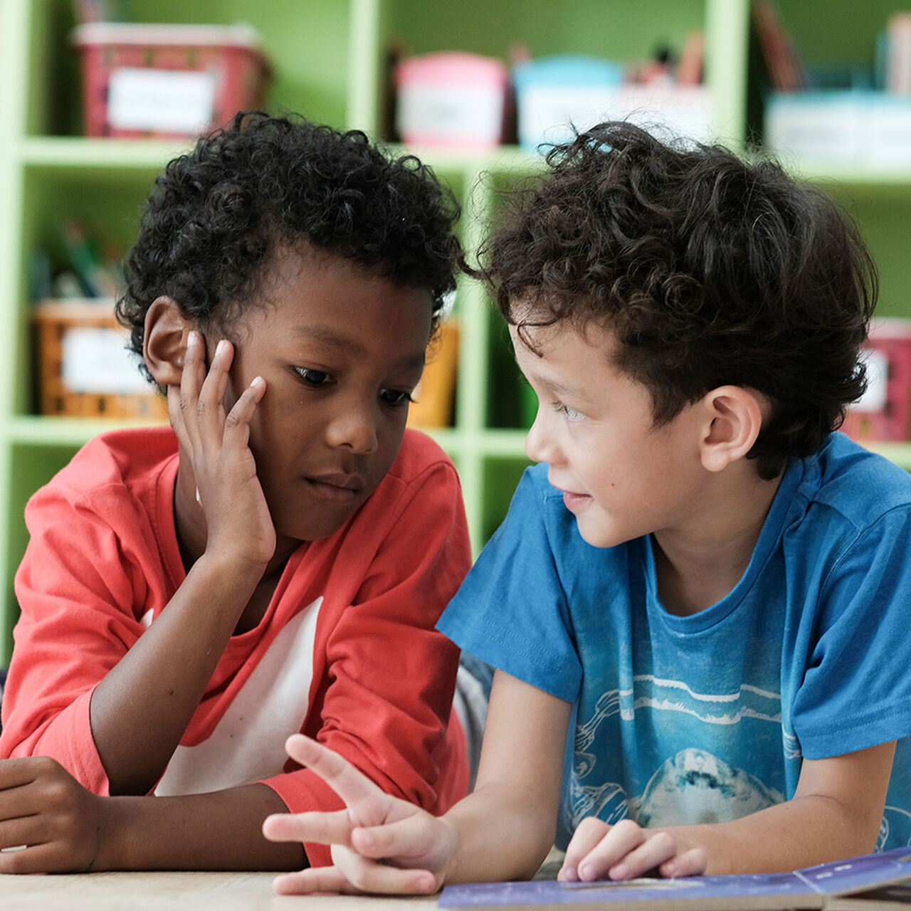 Two children talking to each other at a table image number 0