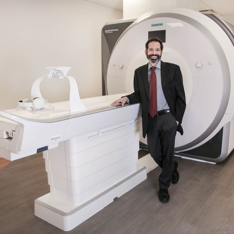 Person in a suit standing in front of an MRI machine