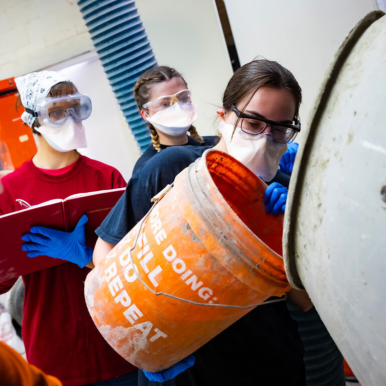 Three students wearing masks and working with cement