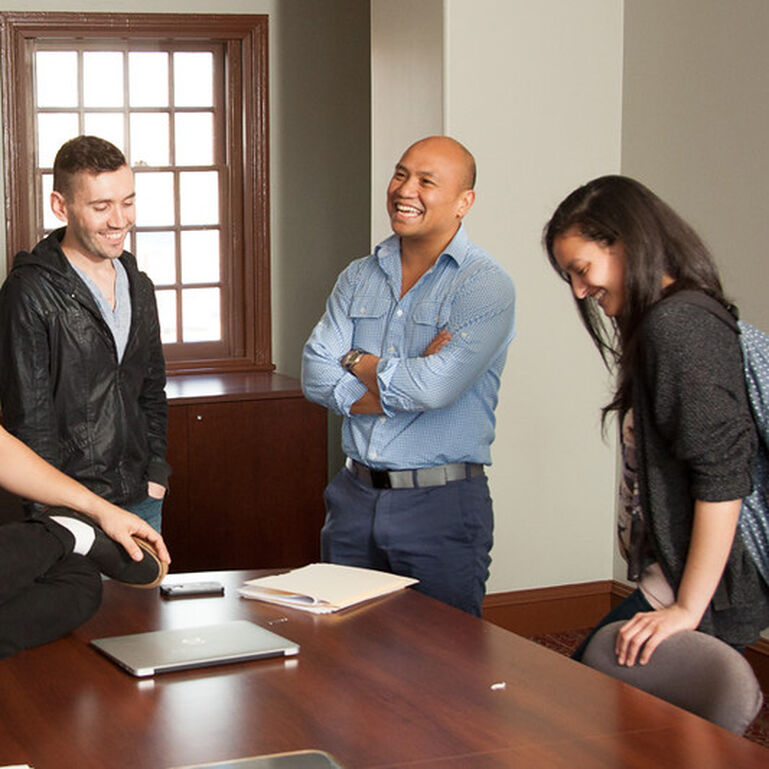 Three people smiling around a conference table