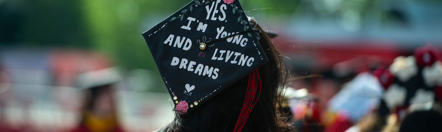 A student's graduation cap which reads "Yes I'm young and I'm living dreams"