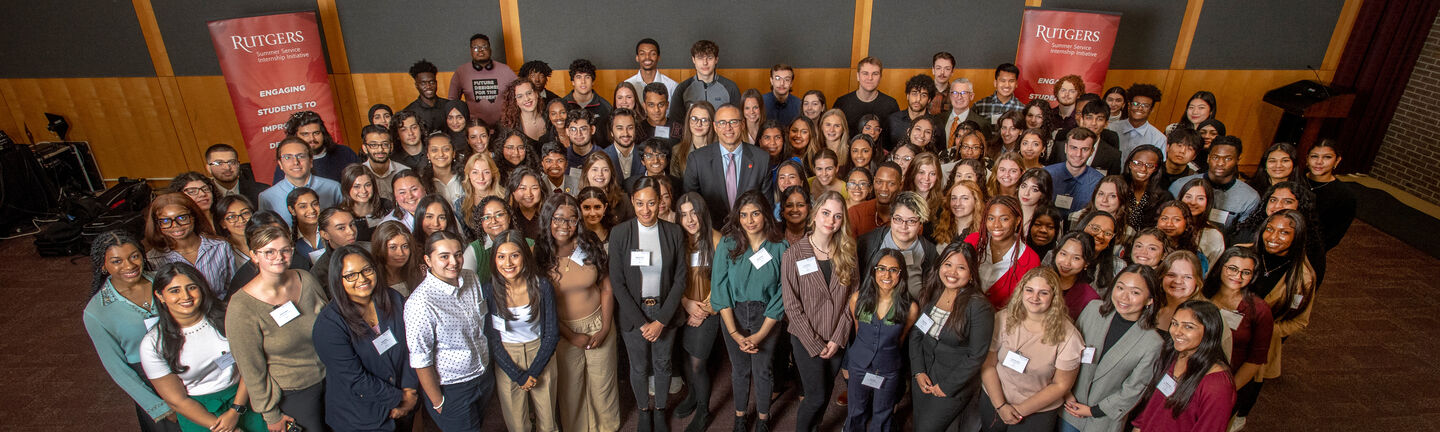The 2023 class of Rutgers Summer Service Internship Initiative students smiling for the camera in a group with Rutgers President Jonathan Holloway